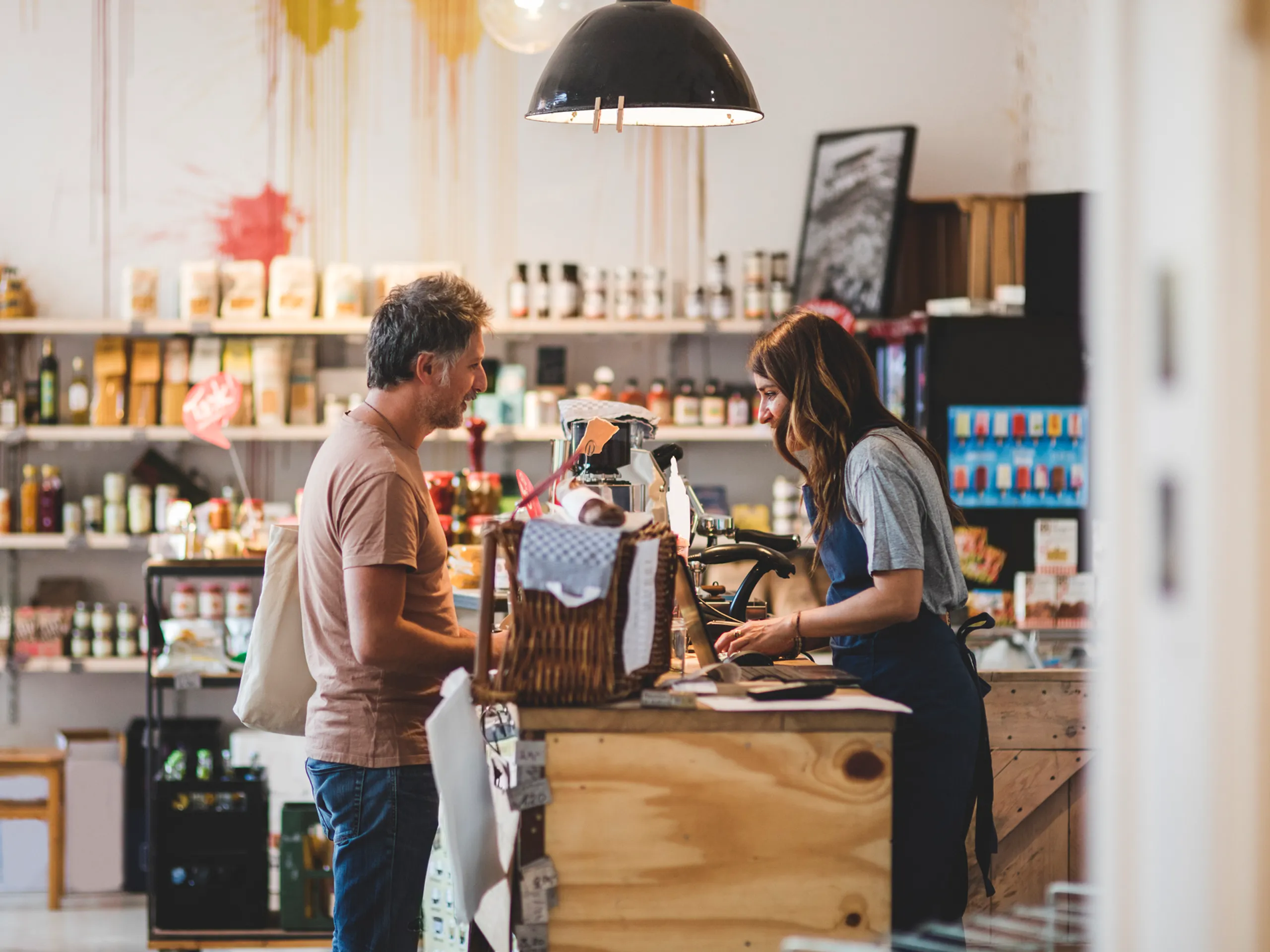 Man and woman talk at the checkout counter in a store.