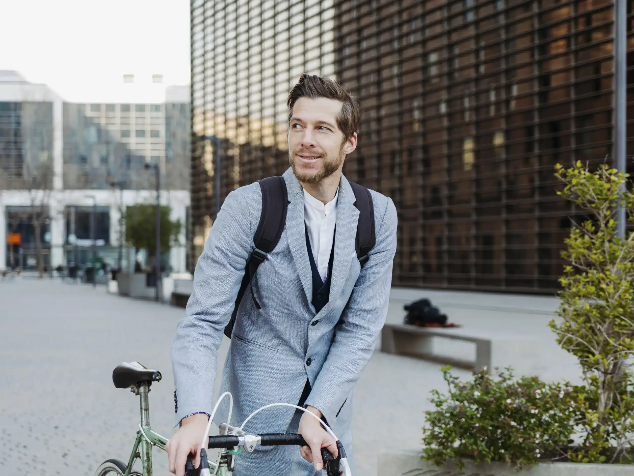 Person standing beside a bicycle in front of a glass-fronted building.