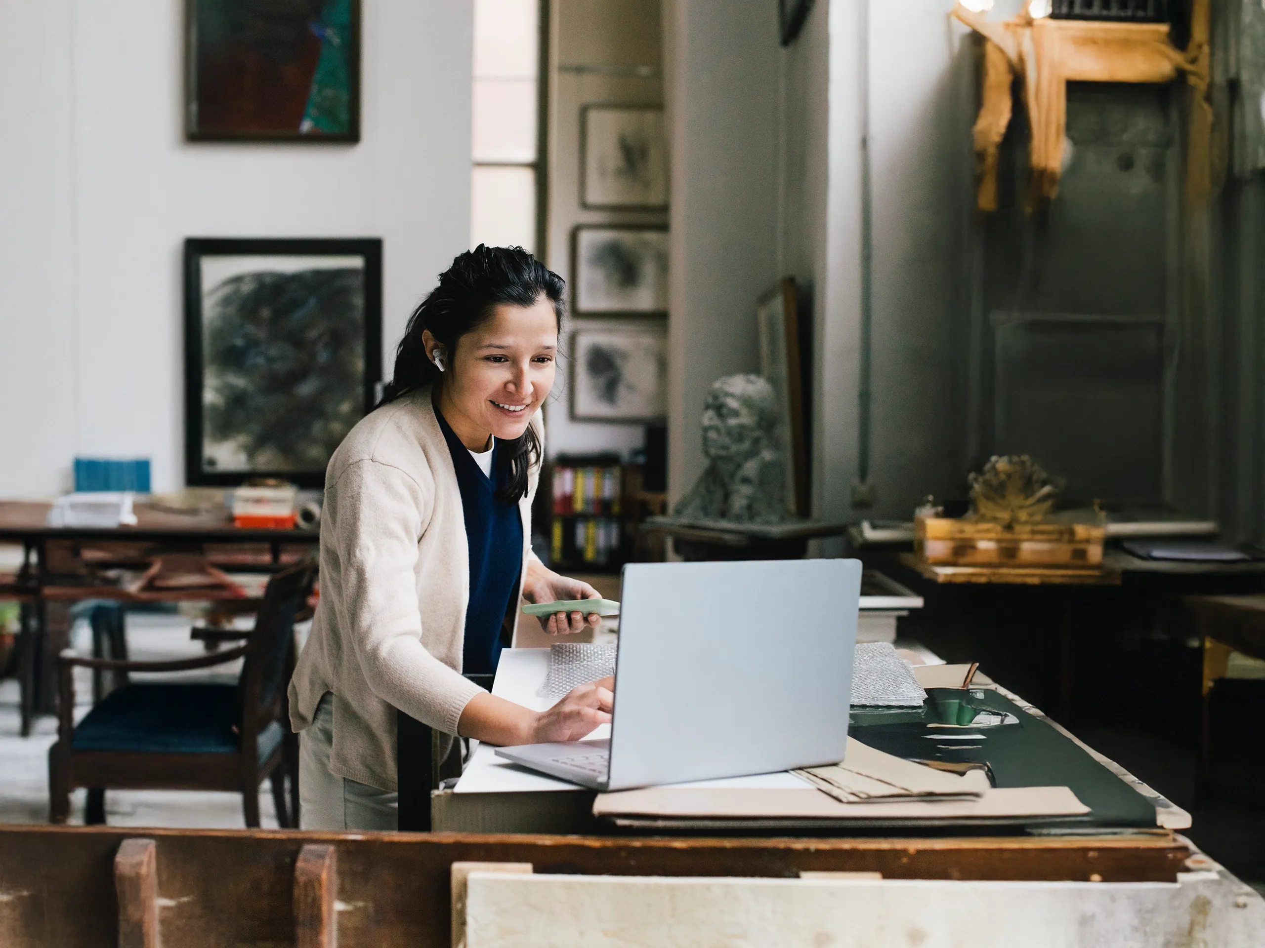 Smiling woman works with a laptop in a creative studio.