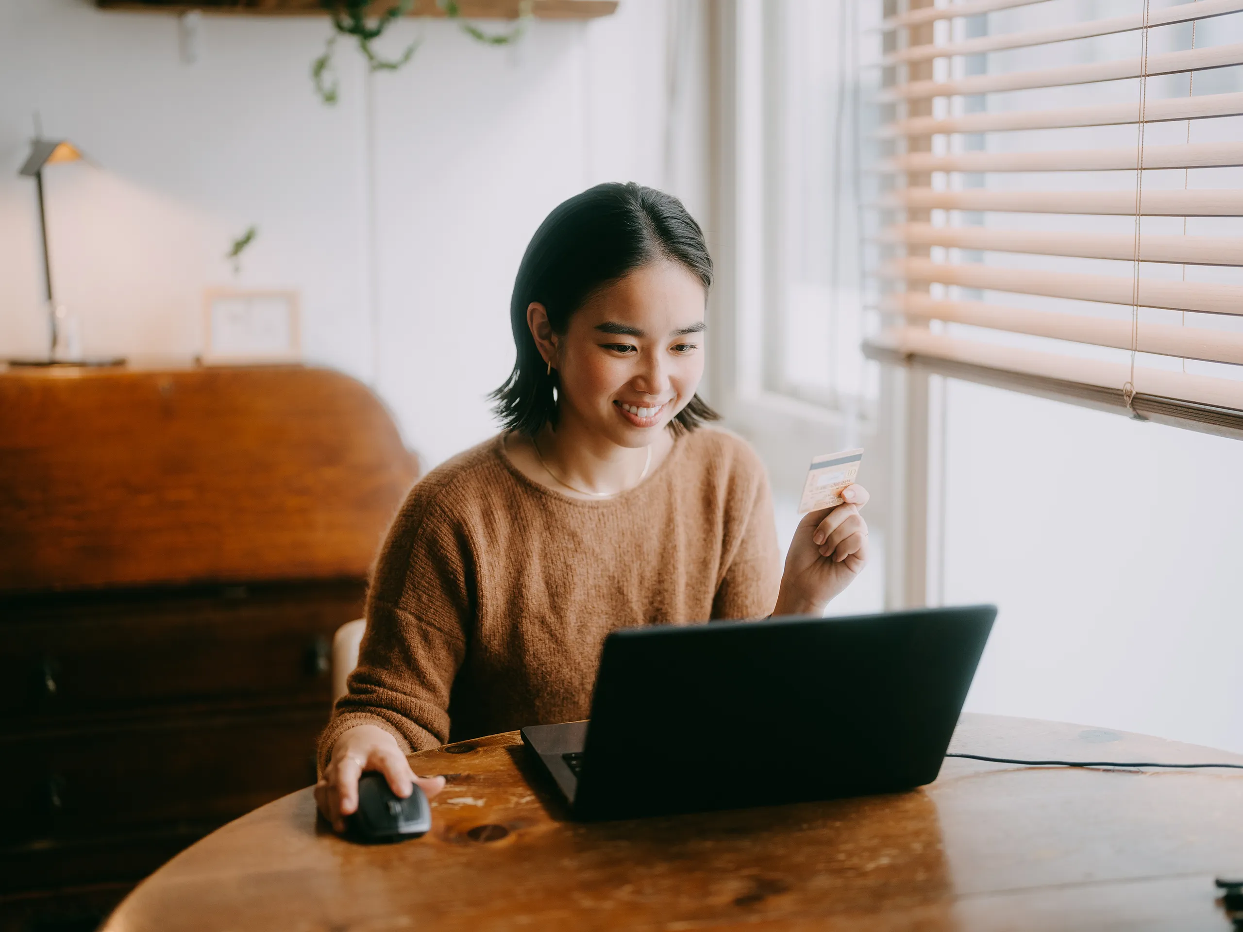 Smiling woman using a laptop and credit card for online shopping.
