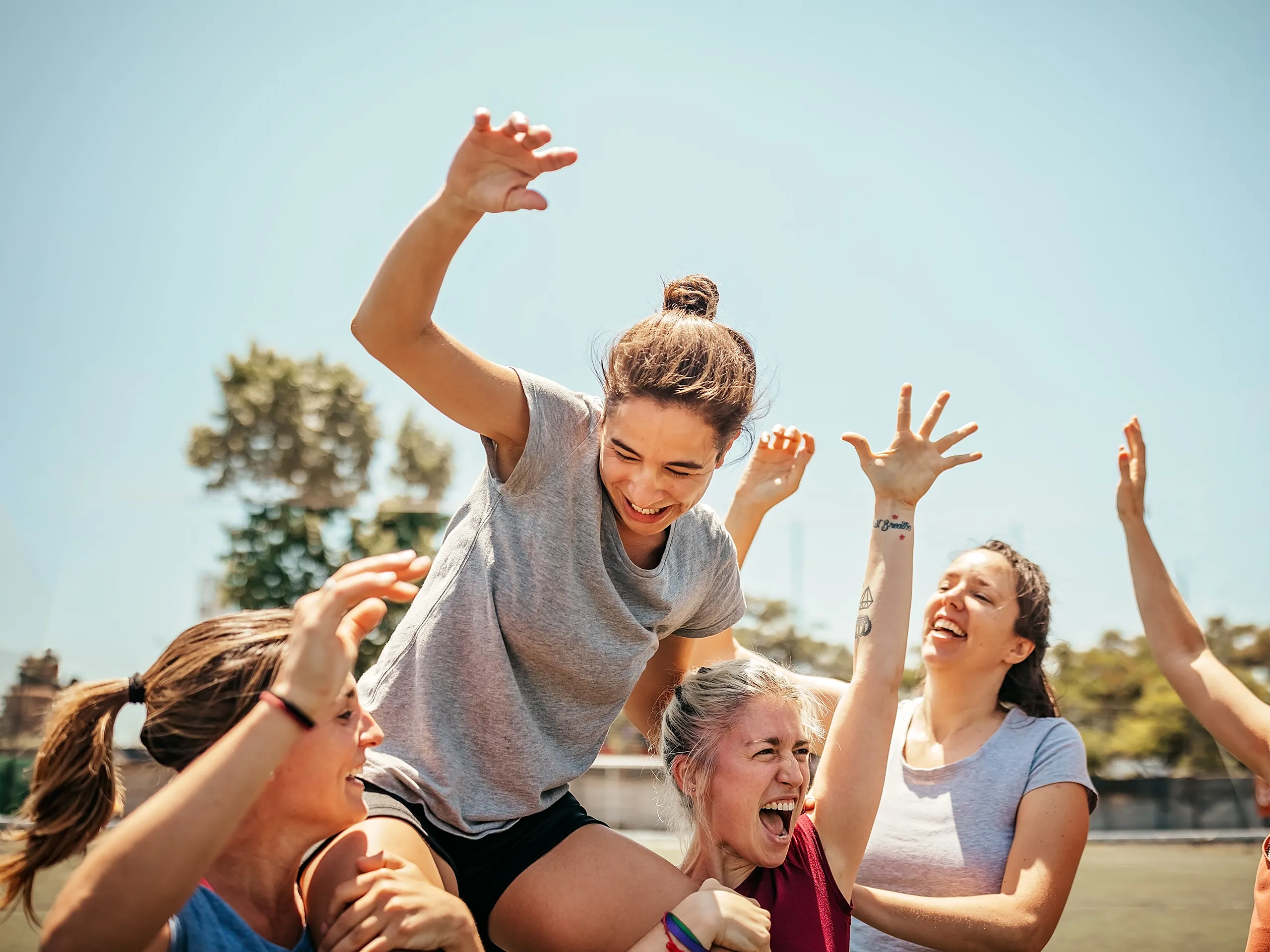 Group of women celebrate together on a sports field.